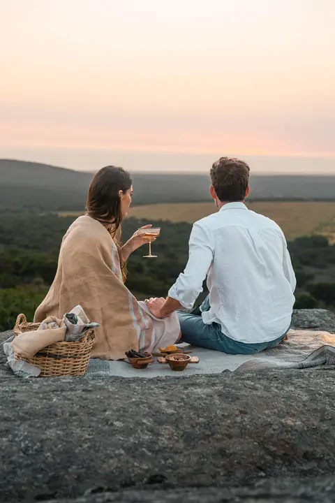 A couple picnic on a rock above the valley