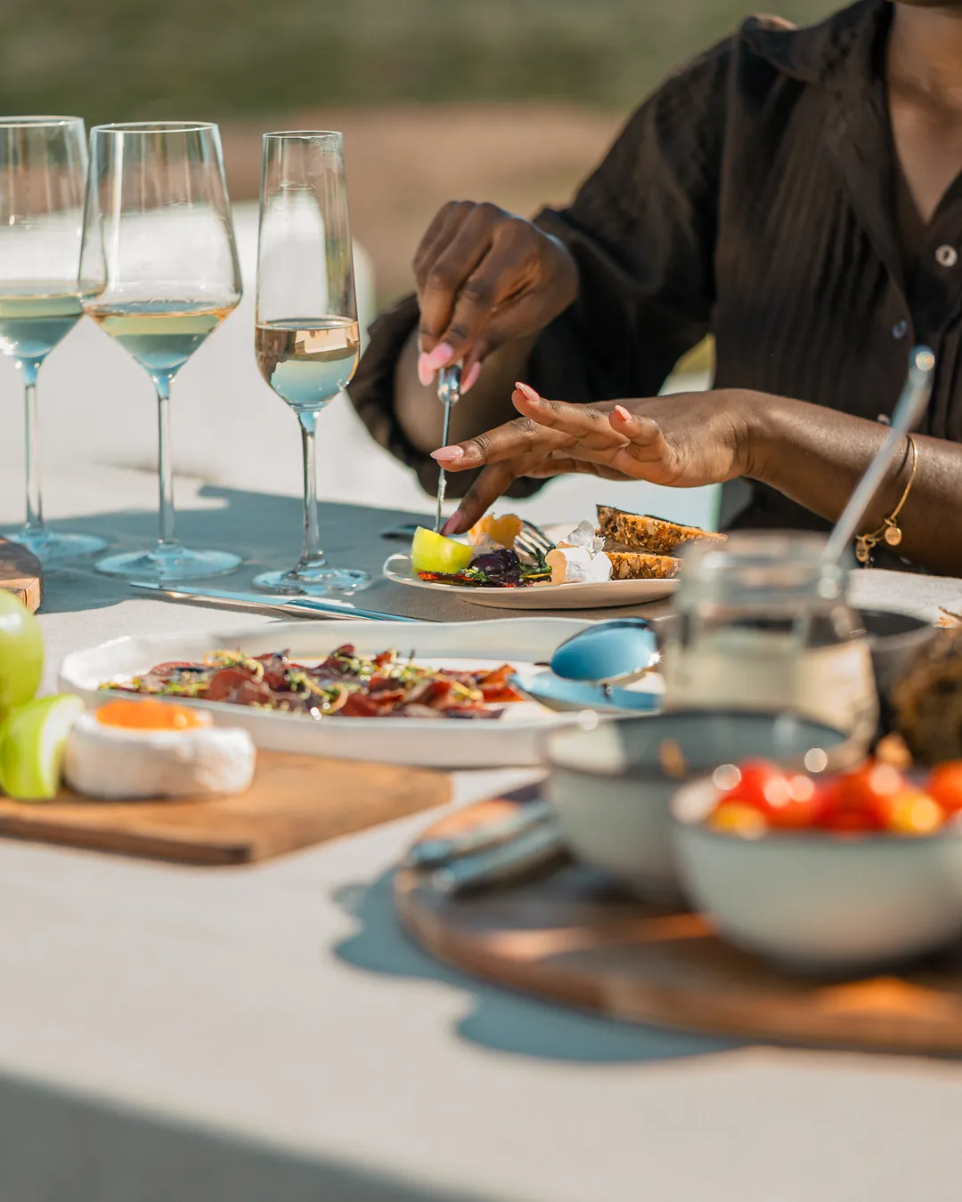 Hands at a tasting table set with wine glasses and small plates, De Wildeveldt