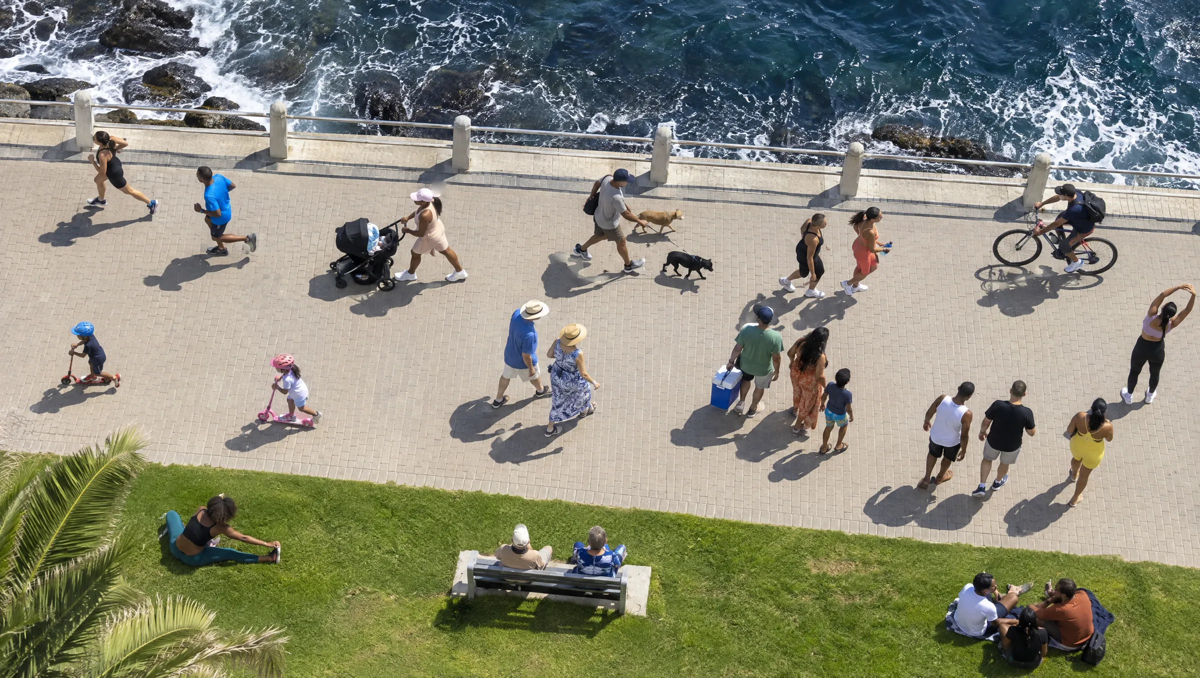 The Sea Point promenade from above on a Saturday morning, busy with walkers, runners and families. A mother with a pram and an older couple on a bench are circled in red.