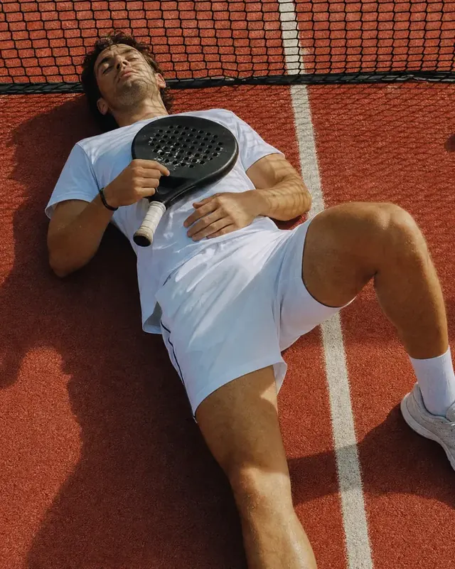 A padel player lies on the court with her racket