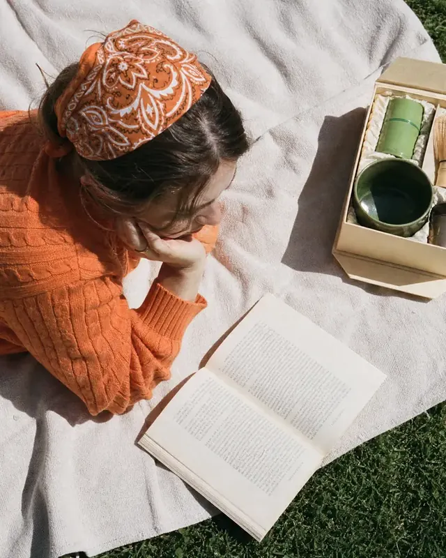 A woman reads on a picnic blanket in the sun
